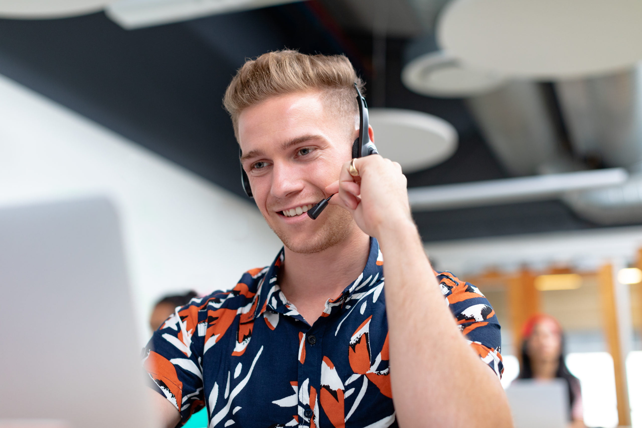 Front view of happy Caucasian male customer service executive talking on headset in a modern office Front view of happy Caucasian male customer service executive talking on headset in a modern office
