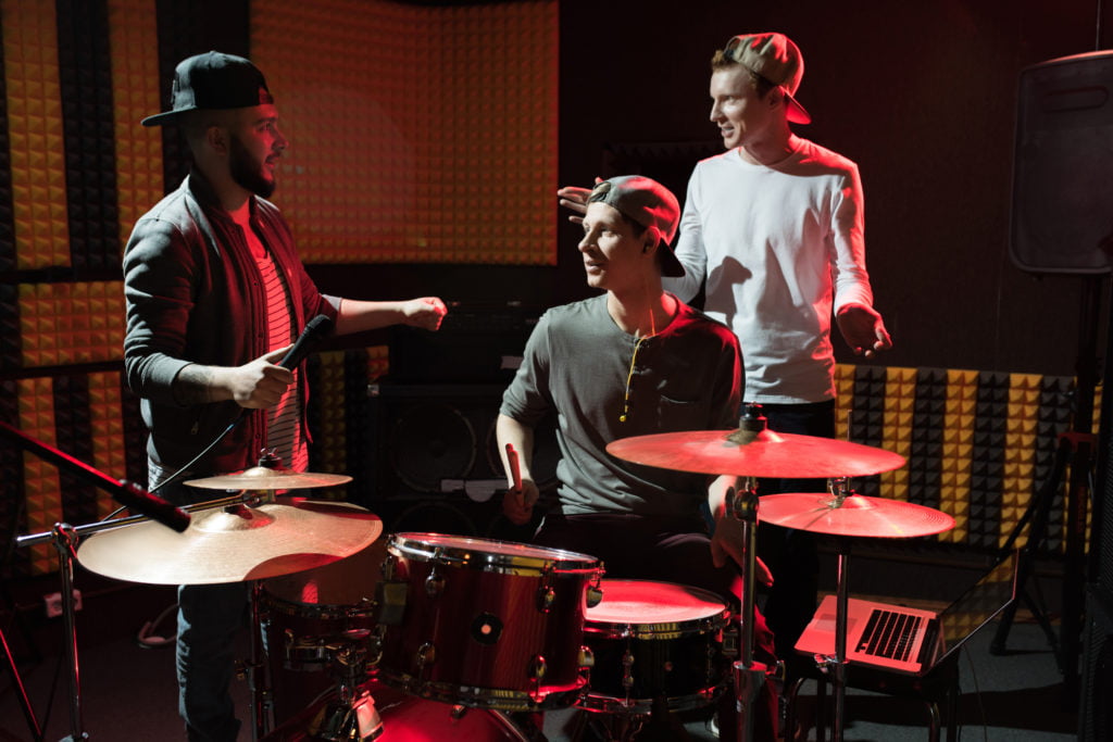Garage Band in Recording Studio Portrait of modern hip-hop band rehearsing in recording studio lit by red lights while making new album