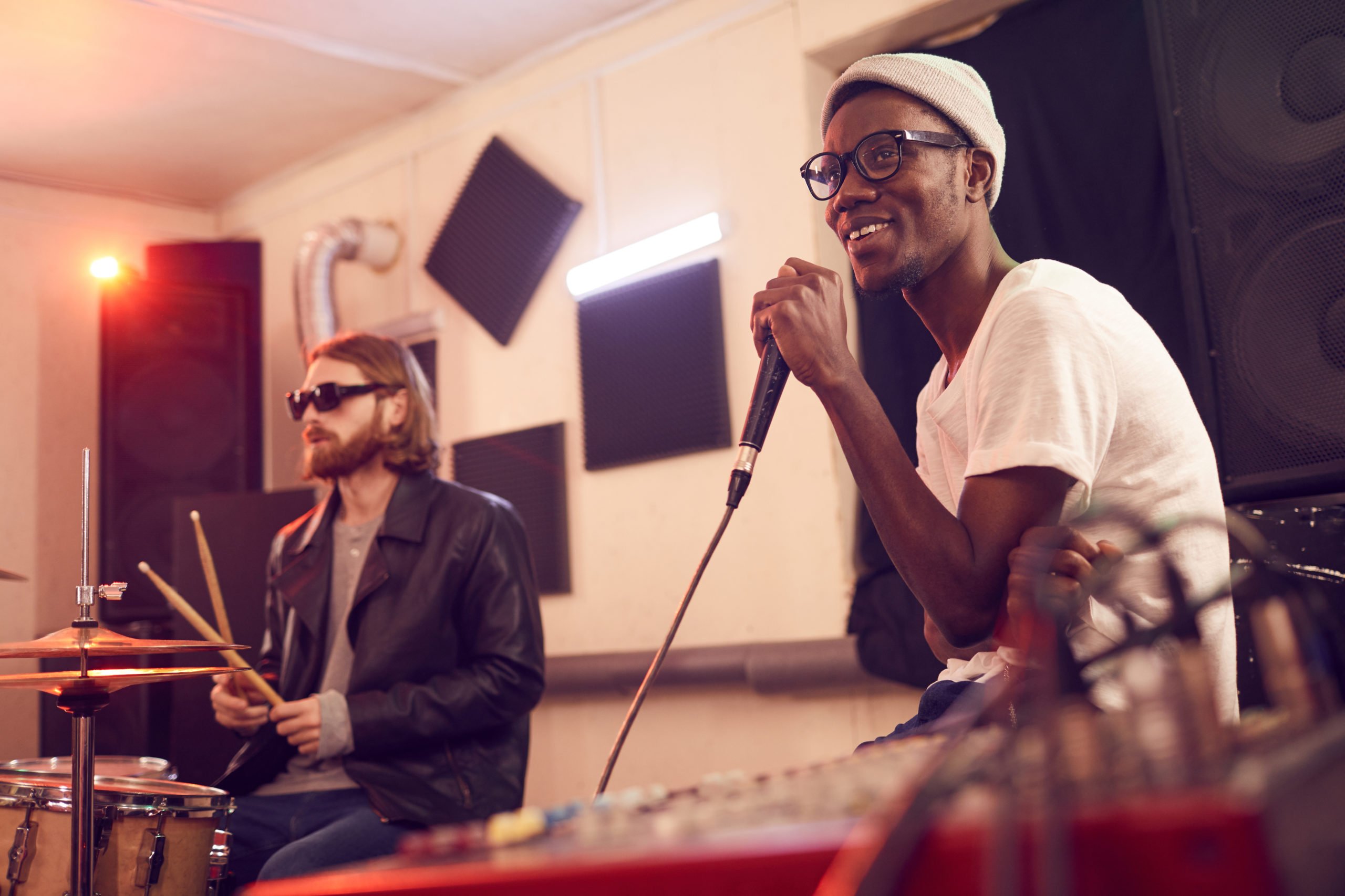 Music Band Enjoying Rehearsal Portrait of contemporary African-American man singing to microphone and smiling happily during rehearsal or concert in music studio, copy space